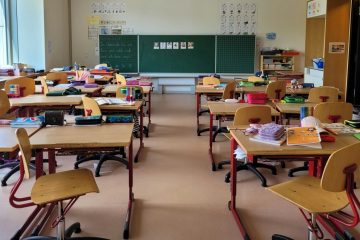 Ein Klassenzimmer mit vielen Tischen und Stühlen.